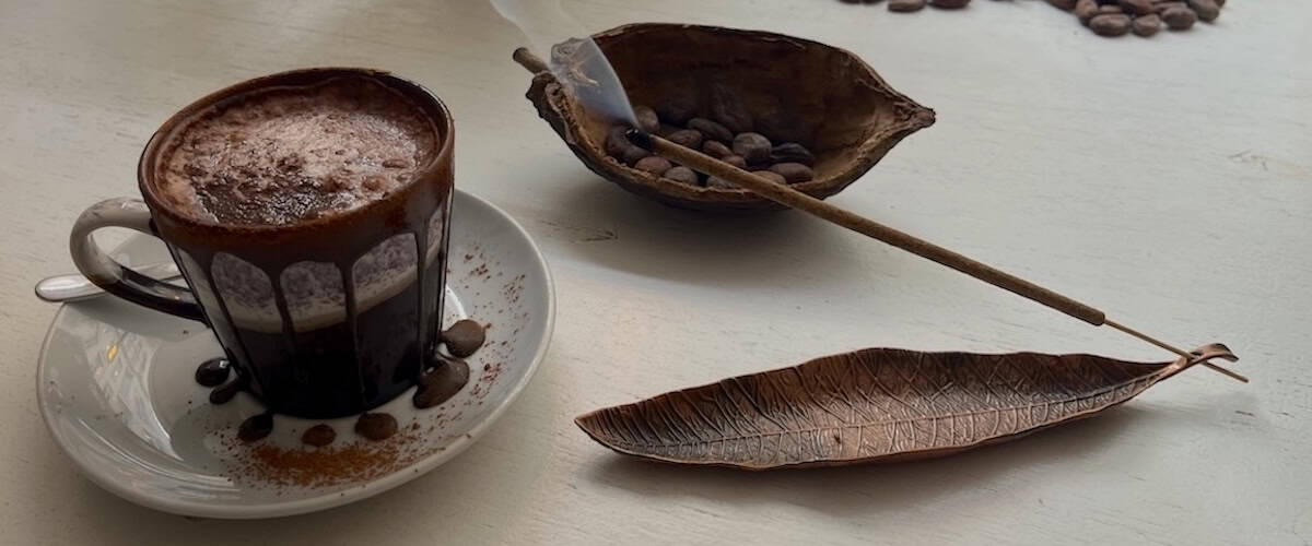 Kaffe med chokolade og kaffebønner på en hvid overflade.