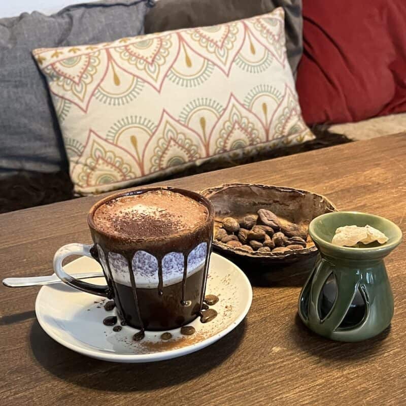 Kaffe med chokolade og krydderier på træbord i hyggelig setting.